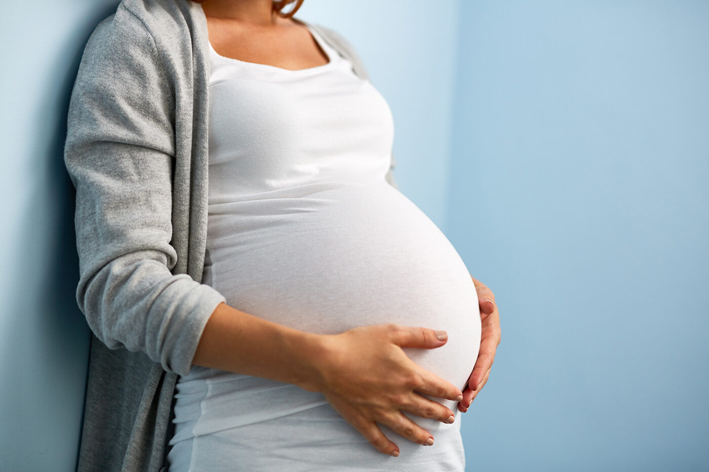 Schwangere Frau hält mit den Händen ihren Bauch
